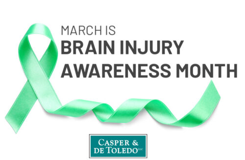 Image of a green ribbon with the text "March is Brain Injury Awareness Month," highlighting the significance of this period. Below the text stands a logo for Casper & de Toledo LLC, showing their dedication to raising brain injury awareness.