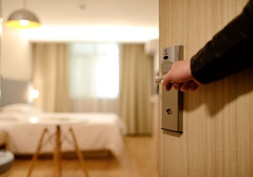 A person opens the door to a bright, tidy hotel room with a neatly made bed, unaware that a potential hotel accident could lead to a Connecticut hotel injury during their stay.